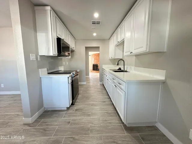 a kitchen with stainless steel appliances a sink stove top oven and cabinets