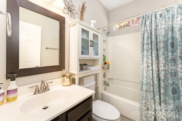 a bathroom with a bathtub shower sink vanity mirror and toilet