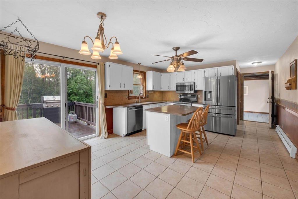 157 Podunk Road Sturbridge, MA 01566 - Photo 8 of 42 a kitchen with stainless steel appliances granite countertop a stove top oven a refrigerator a sink and a dining table with wooden floor
