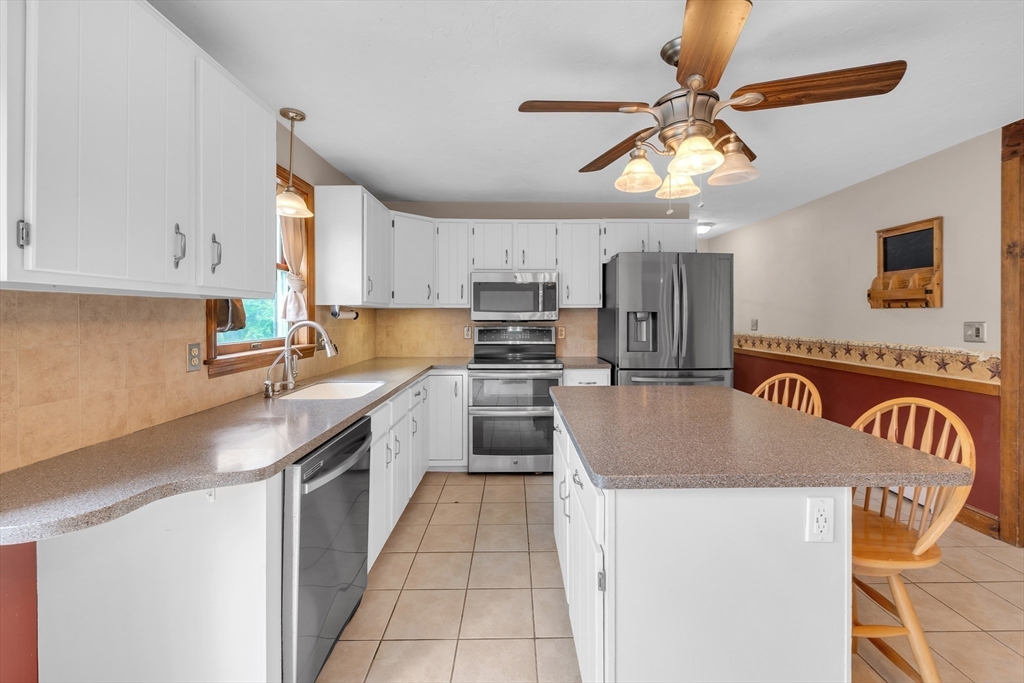 157 Podunk Road Sturbridge, MA 01566 - Photo 10 of 42 a kitchen with kitchen island granite countertop a stove top oven a sink a counter space and cabinets