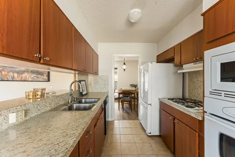 a kitchen with granite countertop a sink a counter space appliances and cabinets