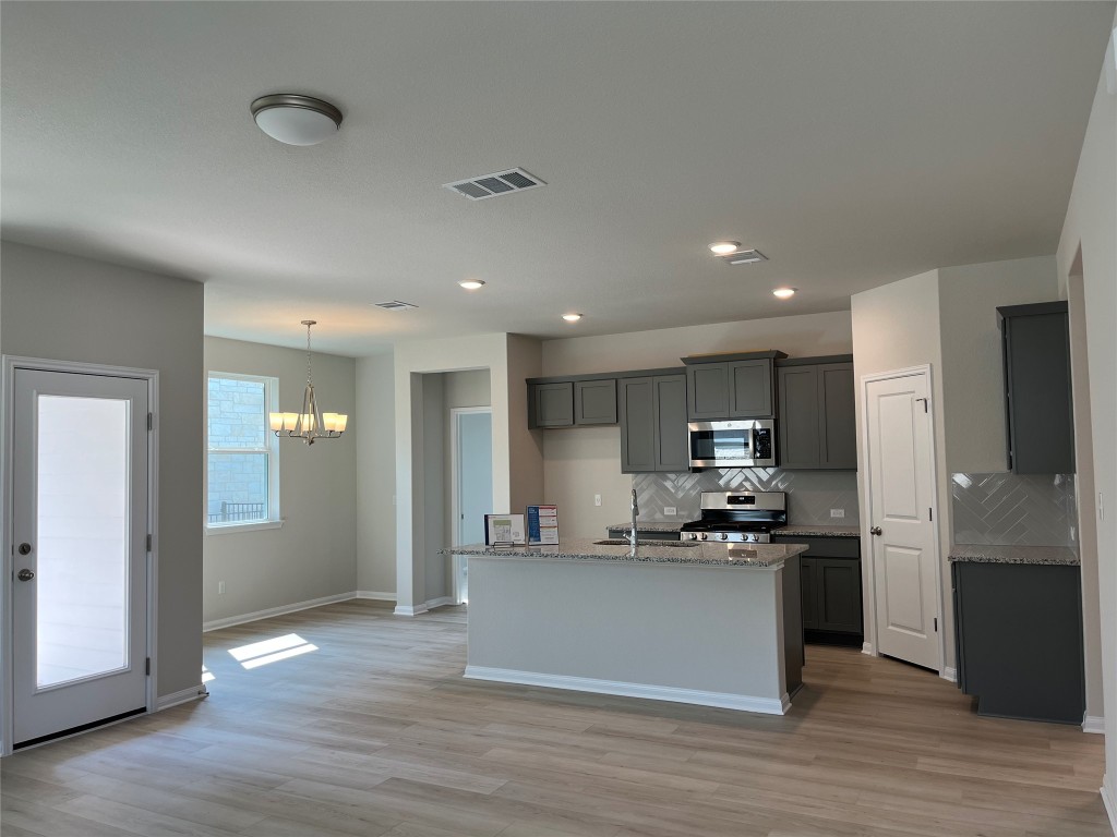130 Spangle Way Kyle, TX 78640 - Photo 4 of 28 a kitchen with stainless steel appliances kitchen island granite countertop a refrigerator and a stove top oven