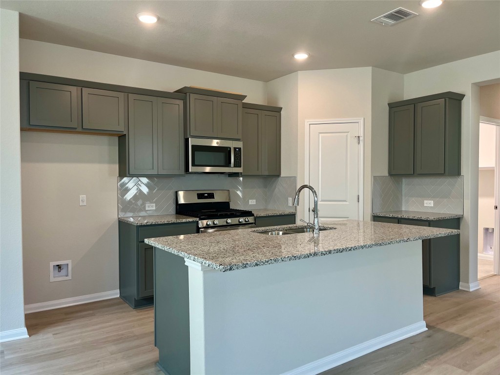 130 Spangle Way Kyle, TX 78640 - Photo 6 of 28 a kitchen with kitchen island granite countertop a sink stainless steel appliances and cabinets