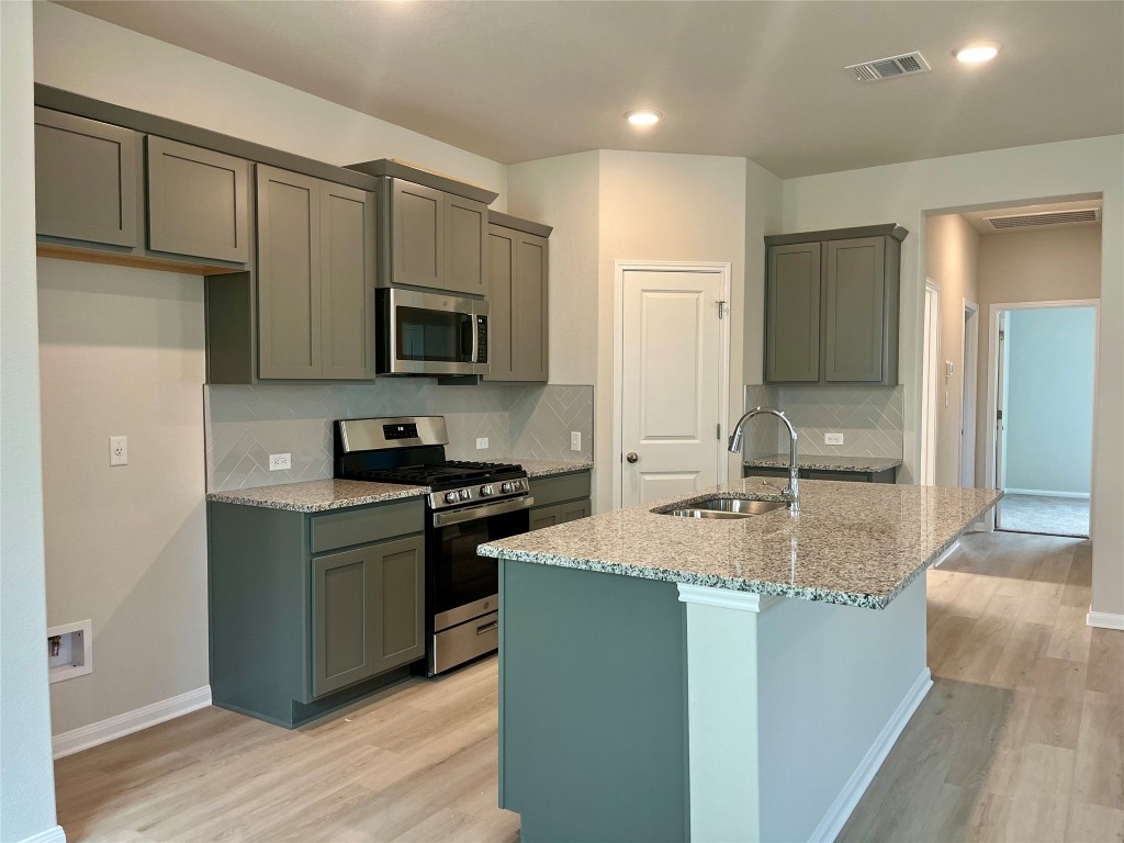 130 Spangle Way Kyle, TX 78640 - Photo 7 of 28 a kitchen with stainless steel appliances granite countertop a stove a sink and a microwave