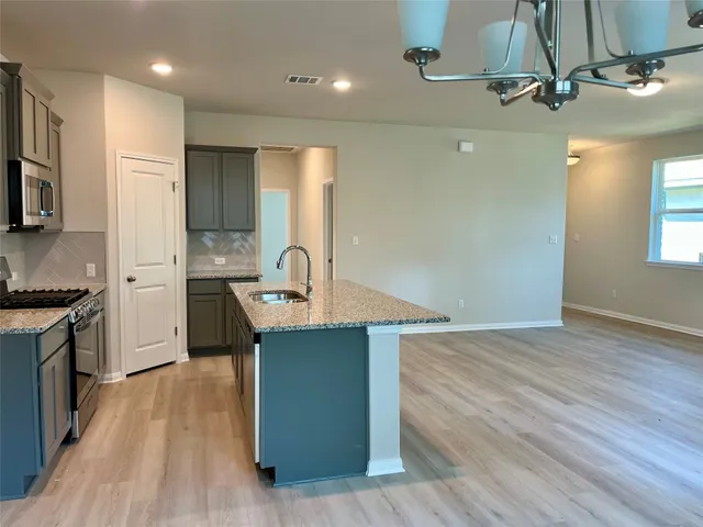 a large kitchen with stainless steel appliances a large counter top a stove a sink and a refrigerator