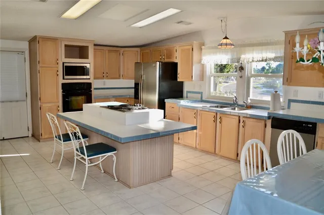a kitchen with stainless steel appliances kitchen island granite countertop a table chairs in it and wooden floors