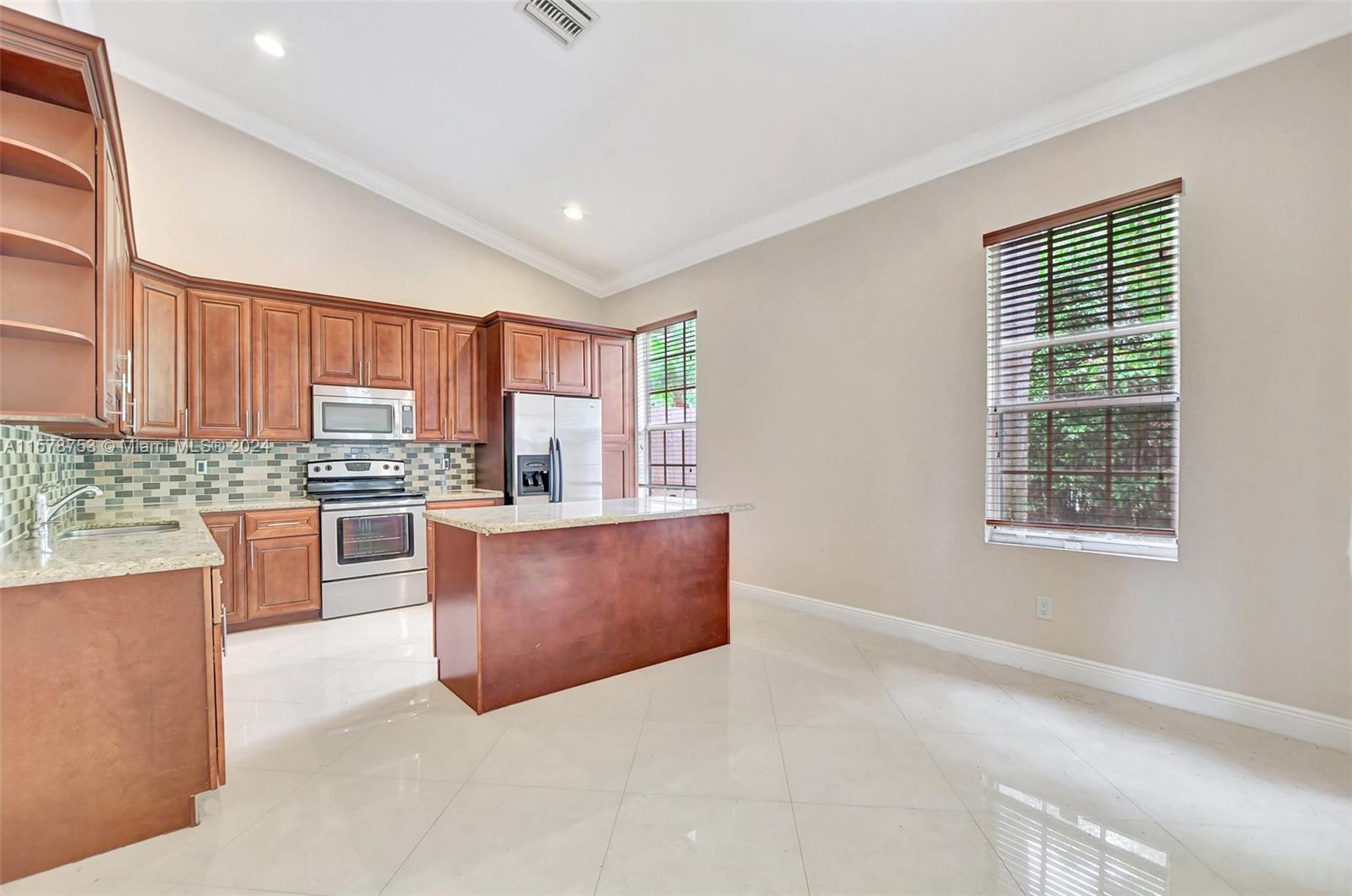 20916 Avenel Run Boca Raton, FL 33428 - Photo 13 of 43 a large kitchen with stainless steel appliances granite countertop a stove a sink dishwasher a refrigerator and a dining table with wooden cabinet