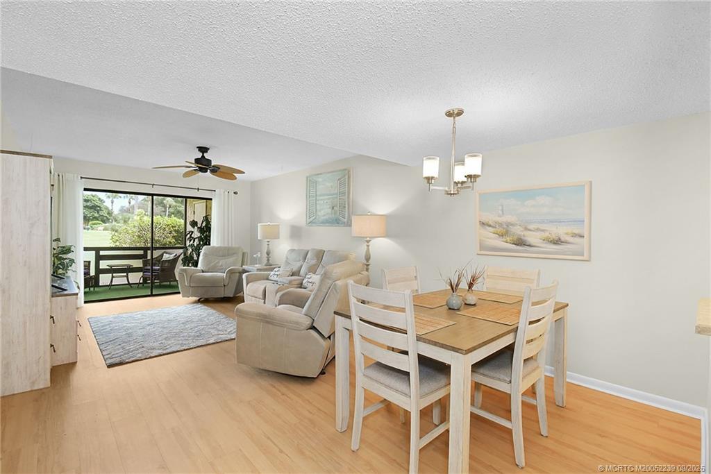 5313 Southeast Miles Grant Road, Unit 102 Stuart, FL 34997 - Photo 11 of 48 a living room with furniture a dining table and a chandelier