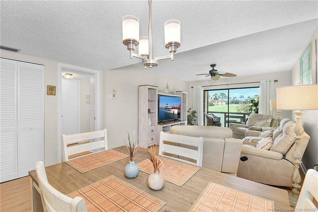 5313 Southeast Miles Grant Road, Unit 102 Stuart, FL 34997 - Photo 12 of 48 a living room with furniture a chandelier and a table