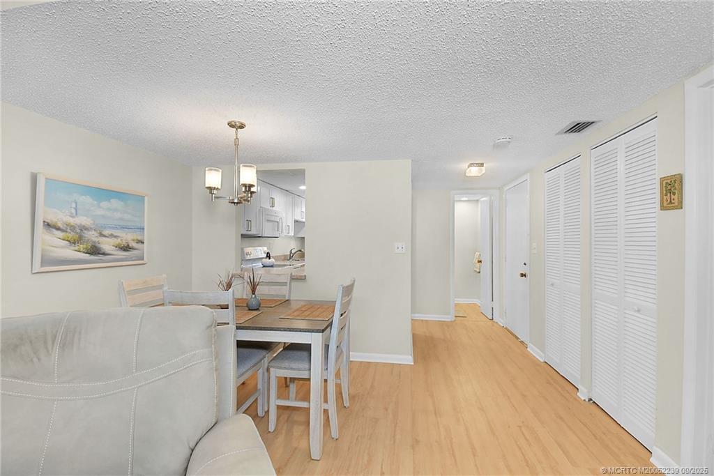 5313 Southeast Miles Grant Road, Unit 102 Stuart, FL 34997 - Photo 17 of 48 a dining room with wooden floor a chandelier a wooden table and chairs