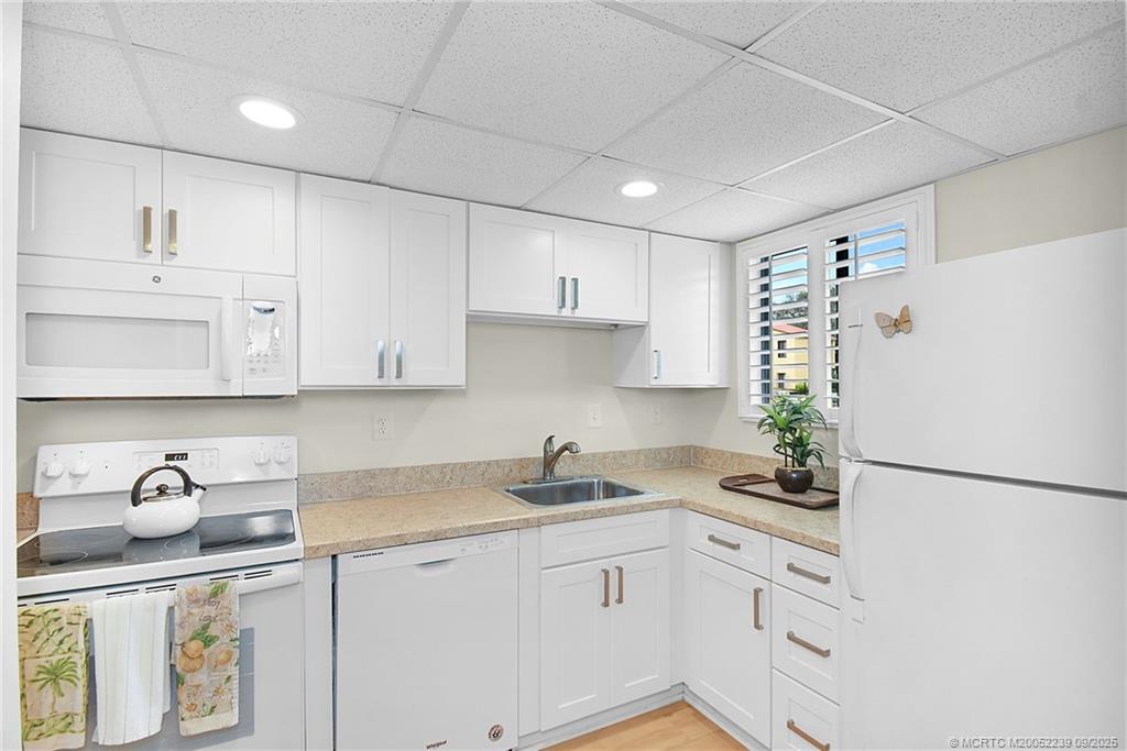5313 Southeast Miles Grant Road, Unit 102 Stuart, FL 34997 - Photo 4 of 48 a kitchen with granite countertop white cabinets and refrigerator