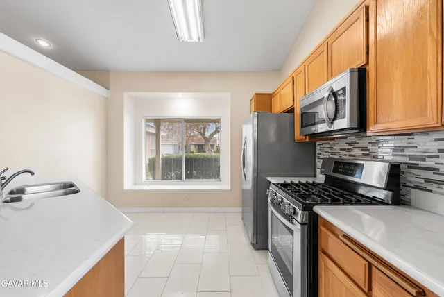 a kitchen with stainless steel appliances granite countertop a stove a sink and a microwave