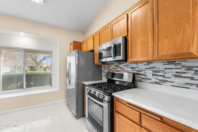 a kitchen with stainless steel appliances a stove a sink a microwave a refrigerator and cabinets