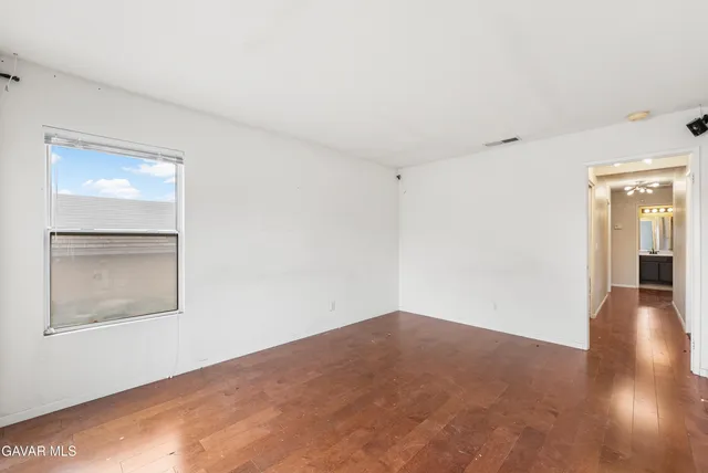 a view of an empty room with wooden floor and a window