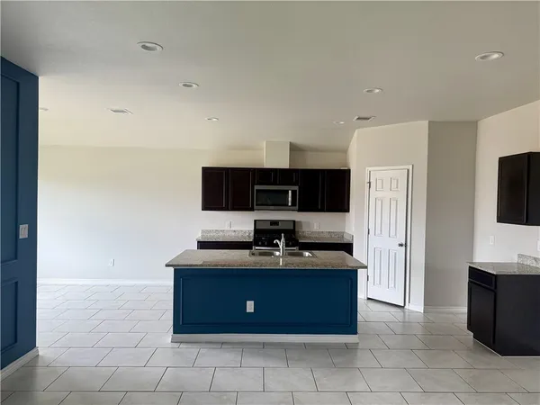 a kitchen with stainless steel appliances granite countertop a stove a sink and a microwave