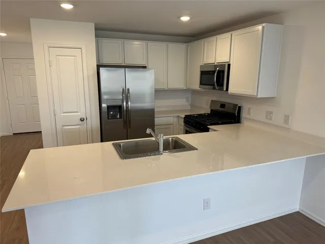 a kitchen with stainless steel appliances a refrigerator microwave stove sink and cabinets