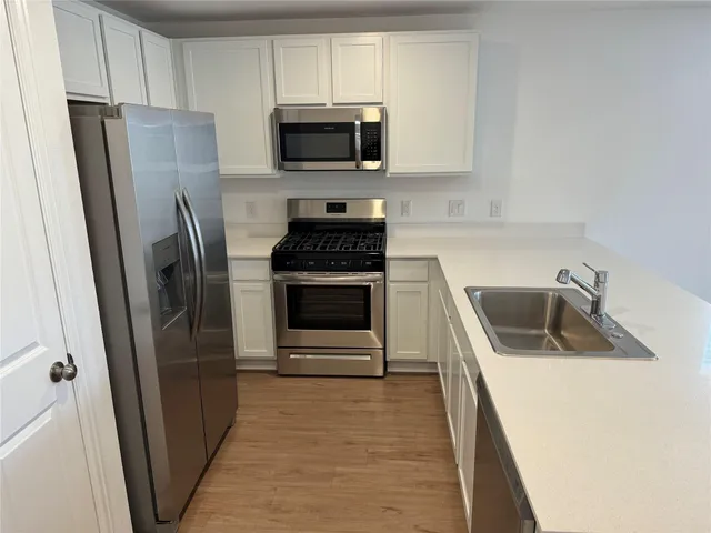 a kitchen with refrigerator a microwave a sink and cabinets