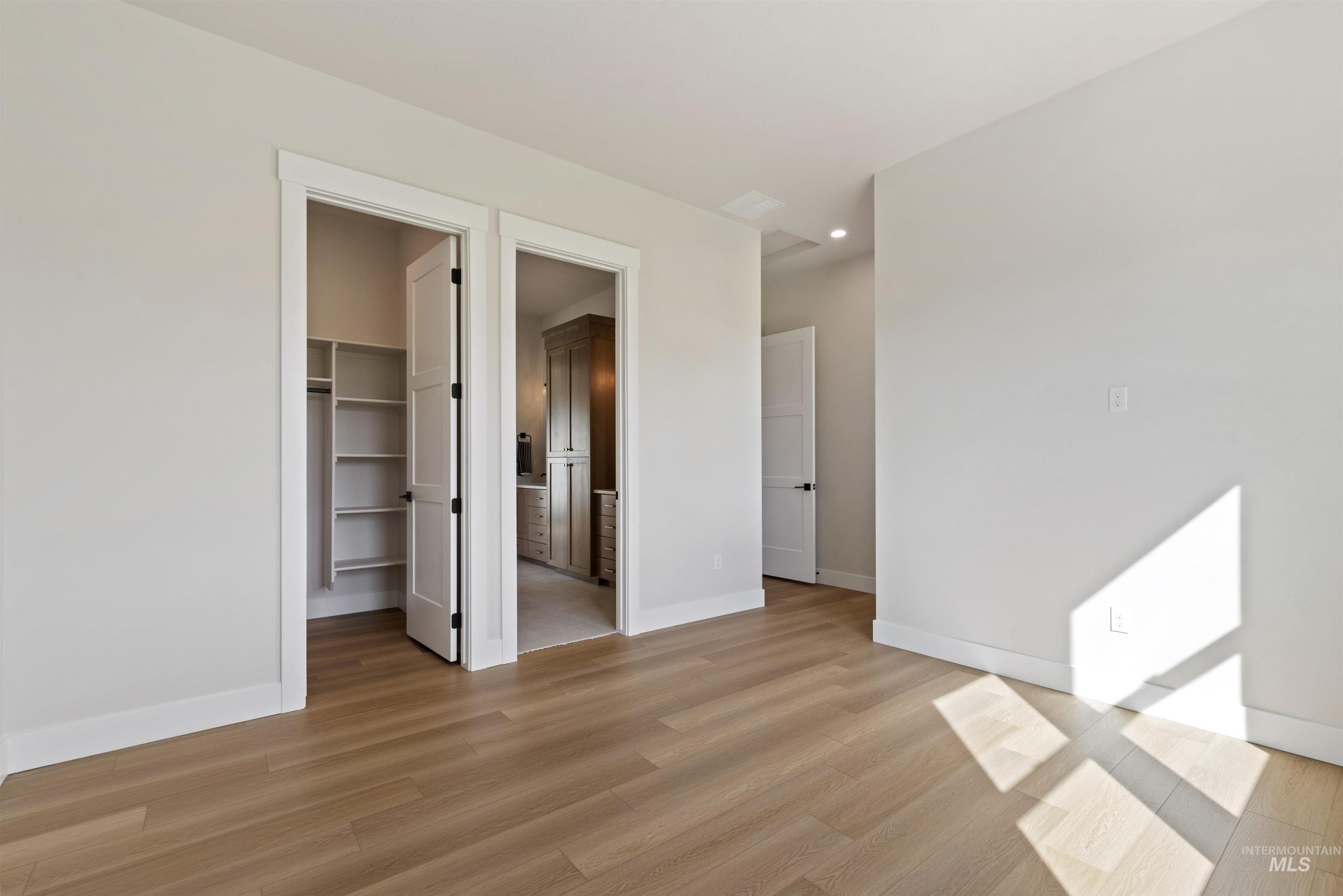 24864 Ardmore Court Caldwell, ID 83607 - Photo 28 of 48 Unfurnished bedroom featuring connected bathroom, a spacious closet, and light wood-type flooring