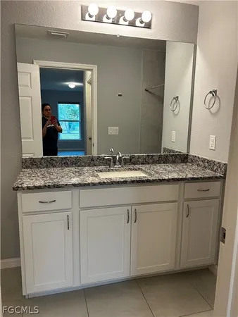 a bathroom with a granite countertop sink and a mirror