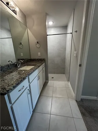 a bathroom with a granite countertop sink a large mirror and a shower