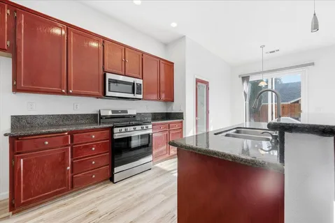 a kitchen with granite countertop wooden cabinets and a stove top oven