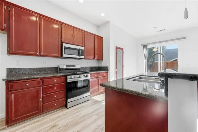 a kitchen with granite countertop wooden cabinets and a stove top oven
