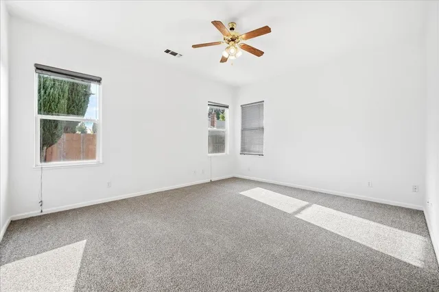 an empty room with a window and a fan