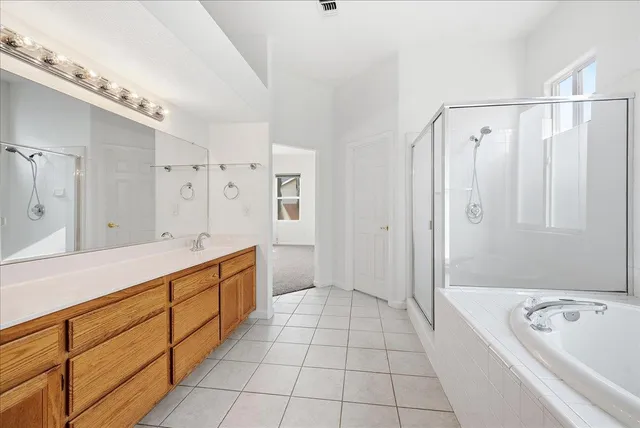 a spacious bathroom with a double vanity sink a mirror a bathtub and shower