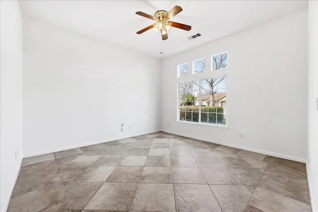 an empty room with windows and fan