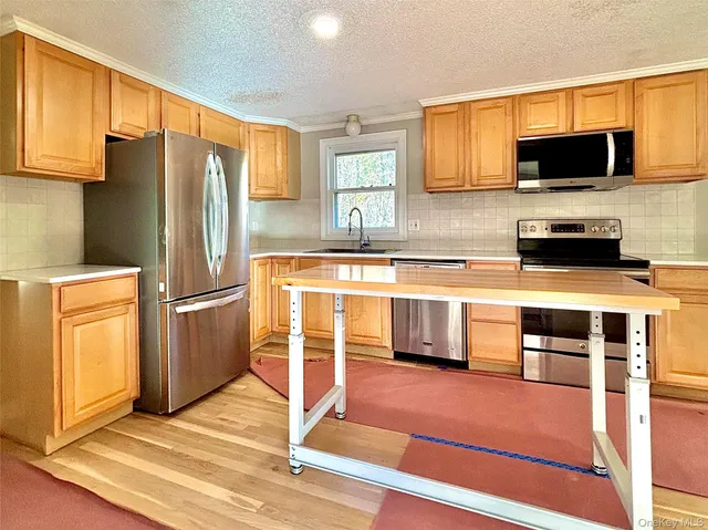 a kitchen with stainless steel appliances wooden cabinets a stove top oven a sink and dishwasher