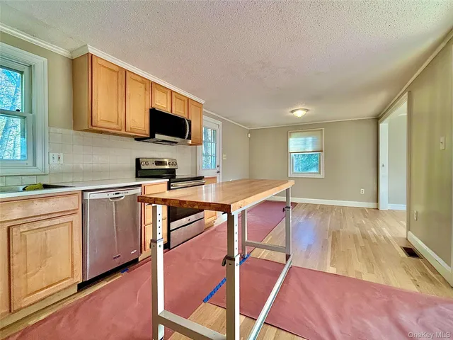 a kitchen with stainless steel appliances granite countertop a stove top oven a sink dishwasher and white cabinets with wooden floor