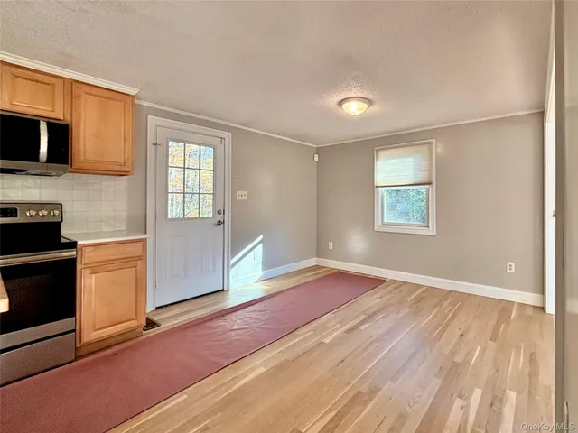 a view of empty room with kitchen and window