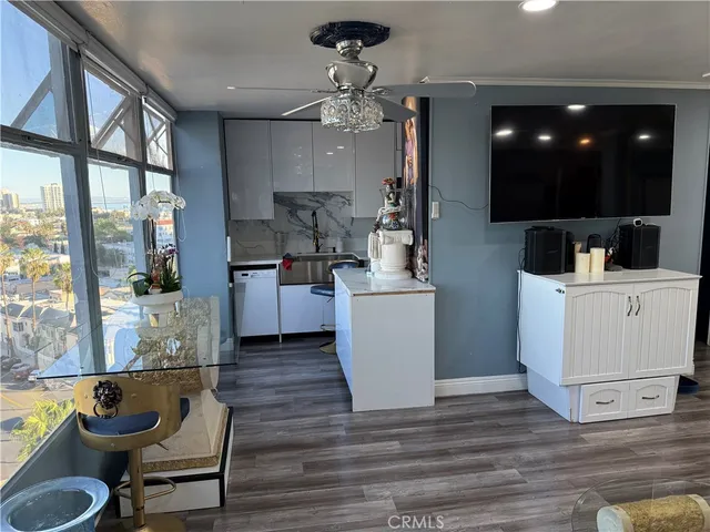 a kitchen with kitchen island a white counter top space a sink a refrigerator and a view of living room