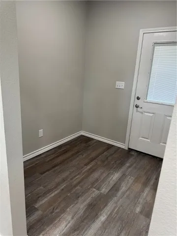 a view of an empty room with wooden floor and closet