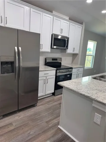 a kitchen with granite countertop a refrigerator stove and microwave