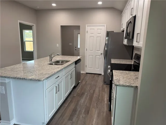 a kitchen with granite countertop a sink stove and refrigerator