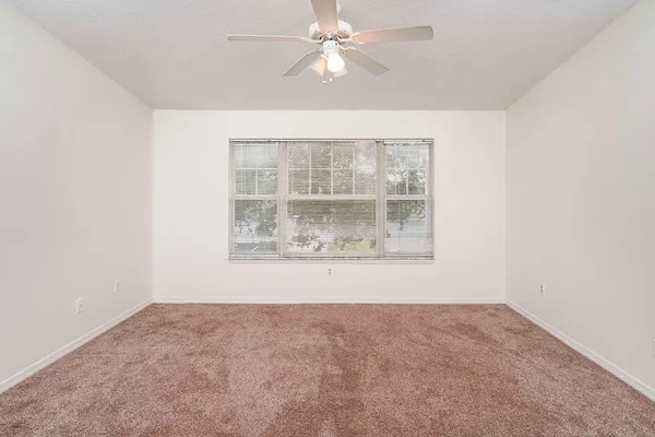 an empty room with a window and ceiling fan