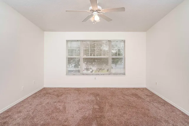 an empty room with a window and ceiling fan