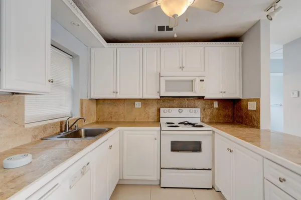 a kitchen with granite countertop white cabinets and white appliances