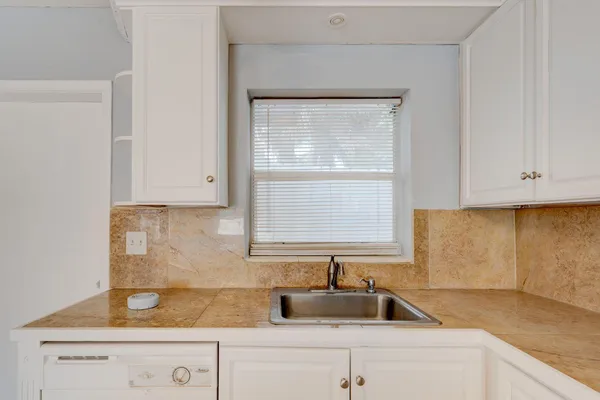 a kitchen with granite countertop white cabinets and a sink