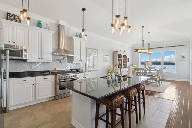 a kitchen with stainless steel appliances kitchen island granite countertop a table chairs sink and cabinets