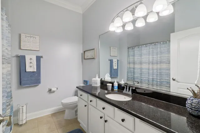 a bathroom with a granite countertop double vanity sink mirror and toilet