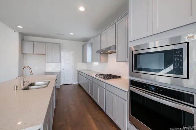a kitchen with kitchen island stainless steel appliances a sink stove and microwave