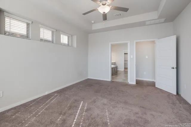 a view of an empty room with chandelier fan