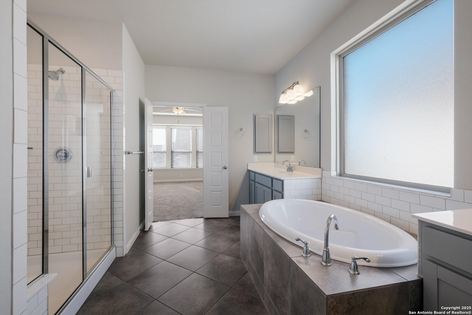 1718 Wind River San Antonio, TX 78258 - Photo 19 of 32 a bathroom with a tub shower vanity and a sink