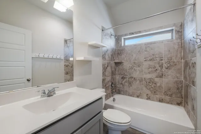 a bathroom with a granite countertop bathtub shower sink vanity mirror and toilet