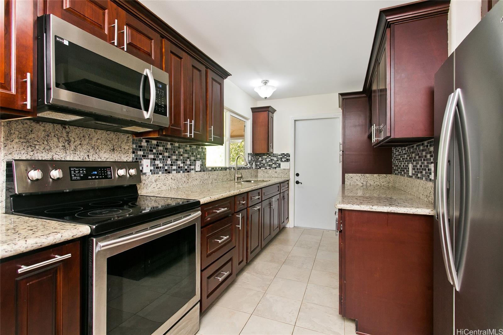 Renovated kitchen with ample cabinet space, stainless steel appliances and granite countertops