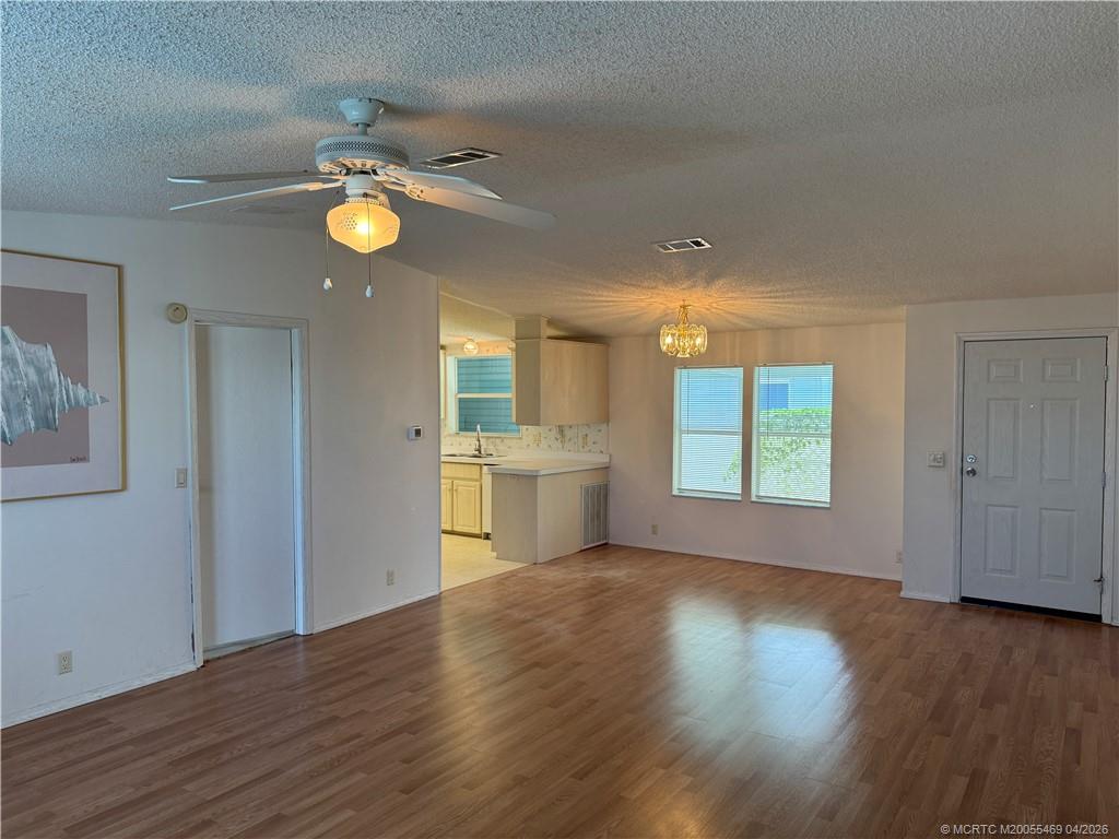 4236 Southeast Sweetwood Way Stuart, FL 34997 - Photo 7 of 50 a view of a kitchen and an empty room with wooden floor and windows