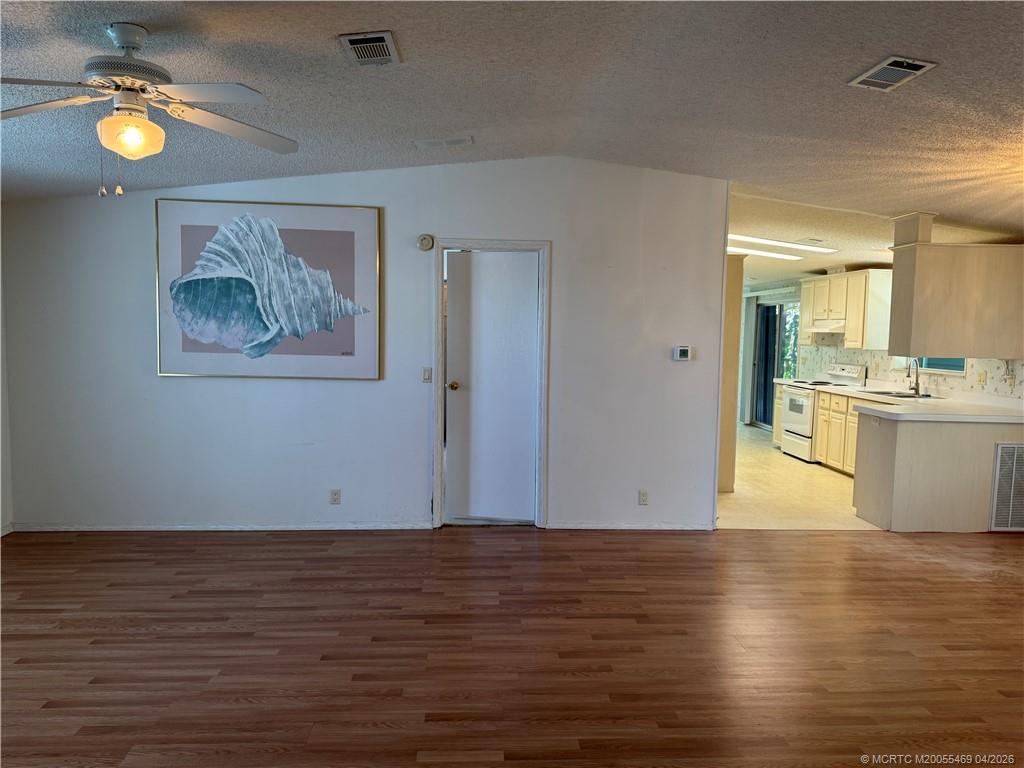 4236 Southeast Sweetwood Way Stuart, FL 34997 - Photo 8 of 50 a view of an empty room with kitchen and painting on the wall