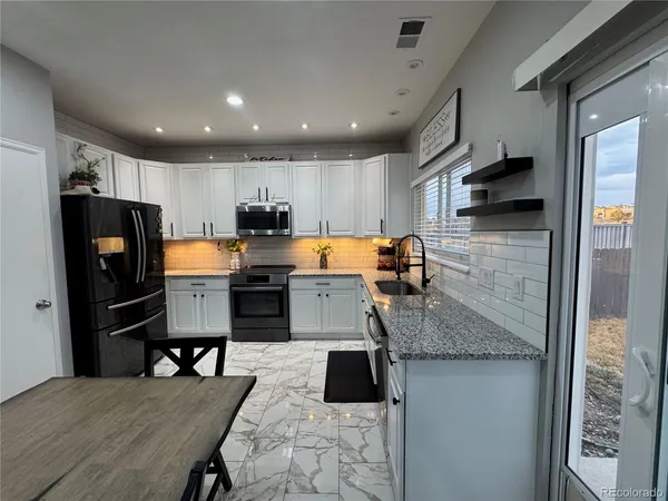 a kitchen with stainless steel appliances granite countertop a sink refrigerator and microwave